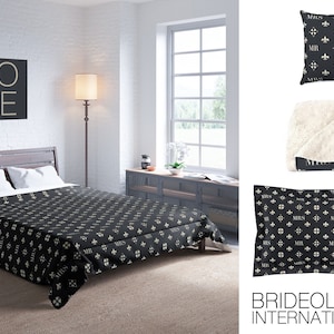 May include: A black and white patterned throw blanket with a white sherpa lining. The blanket features a repeating pattern of fleur-de-lis and the words "Mr." and "Mrs." in a script font. The blanket is displayed on a bed with a black and white patterned duvet cover. The word "LOVE" is displayed on a black square canvas on the wall behind the bed.