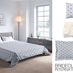 May include: A grey and white patterned bedspread with a grey throw pillow and a grey throw blanket. The throw pillow and blanket feature a repeating pattern of the words "Mr." and "Mrs." with a fleur-de-lis design. The bedspread is on a bed with white sheets and a white headboard. The word "LOVE" is written on a framed picture hanging on the wall behind the bed.