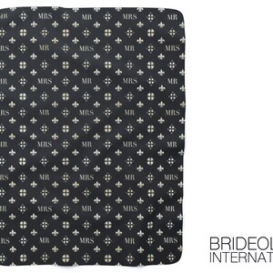 May include: Black and white fabric with a repeating pattern of the words "MR" and "MRS" in a white font. The pattern also includes a white fleur-de-lis design. The fabric has a slightly textured surface. The text "BRIDEOLOGY INTERNATIONAL" is printed in white at the bottom right corner of the fabric.