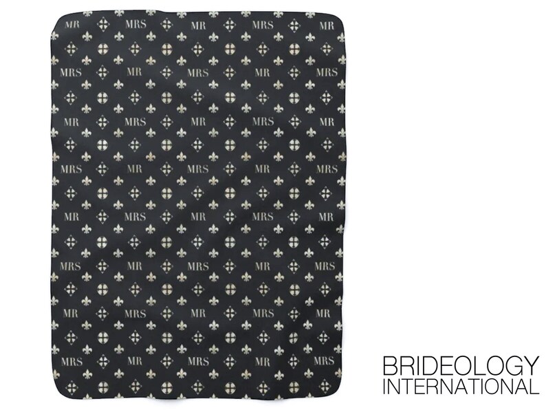 May include: Black and white fabric with a repeating pattern of the words "MR" and "MRS" in a white font. The pattern also includes a white fleur-de-lis design. The fabric has a slightly textured surface. The text "BRIDEOLOGY INTERNATIONAL" is printed in white at the bottom right corner of the fabric.