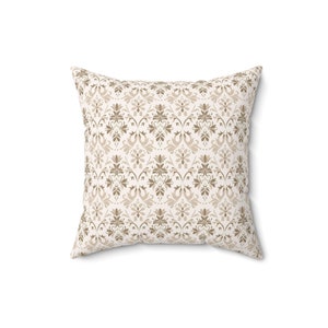 May include: A white throw pillow with a brown damask pattern.