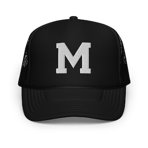 May include: Black trucker hat with a white embroidered letter "M" on the front.
