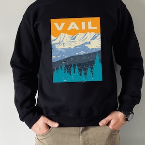 May include: Black sweatshirt with a graphic print of a mountain range and trees. The text "VAIL" is printed in orange on the graphic.