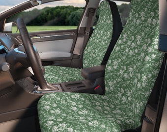 May include: A pair of green car seat covers with a white floral pattern. The covers are installed in the front seats of a car.