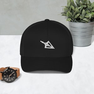 May include: A black baseball cap with a white embroidered arrowhead design. The cap has a mesh back and a curved brim.