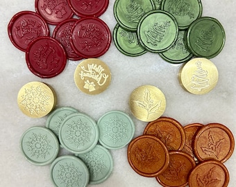 May include: A collection of circular wax seals in red, green, light green, and copper colors, featuring embossed designs of Merry Christmas text with bells, Christmas trees, snowflakes, and holly leaves, alongside three brass stamp heads.