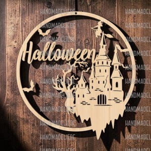 Könnte beinhalten: Ein kreisförmiger Wandbehang aus hellem Holz mit einem lasergeschnittenen Motiv aus einem Schloss, einem kahlen Baum, Fledermäusen und einer Hexe auf einem Besen. Das Wort Halloween ist in Schreibschrift im oberen Teil des Rahmens ausgeschnitten.