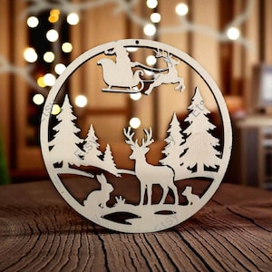 May include: A circular light-coloured wooden ornament featuring a laser-cut design of a forest scene. The cutout depicts a deer standing in the centre, a rabbit to the left, a small animal to the right, pine trees, and Santa in a sleigh above.