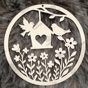Könnte beinhalten: Runde Holzdekoration mit einem Vogelhaus, zwei Vögeln und Blumen. Das Design umfasst einen Ast mit Blättern und einen dekorativen Rand. Das Stück ist unbemalt und kann individuell gestaltet werden. Die Maße sind in Zentimetern.