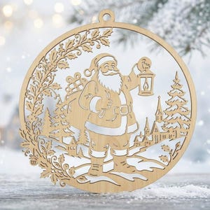 Könnte beinhalten: Ein kreisförmiger Weihnachtsanhänger aus hellem Holz mit einem Laserschnitt-Design, das den Weihnachtsmann mit einem Geschenkesack und einer Laterne zeigt. Das Motiv umfasst ein Dorf mit Kirche, Tannenbäumen und dekorativen Stechpalmenblättern.