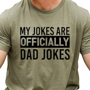 a man wearing a military green t - shirt that says, my jokes are officially