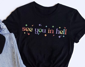 May include: Black t-shirt with the text "see you in hell" in rainbow colors. The text is surrounded by small rainbow stars.