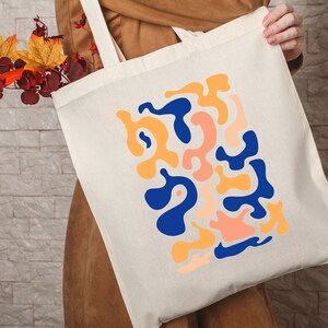 a person holding a tote bag with a design on it