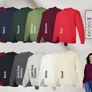 Woman wearing a cream-colored t-shirt with the phrase 'This Awesome Mom Belongs to James' in bold black text, featuring a cute blue handprint design. Paired with distressed blue jeans and layered jewelry, this personalized Mother's Day gift shirt is perfect for proud moms.
