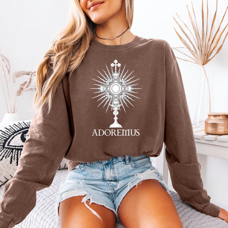 Catholic t-shirt featuring a white Eucharistic monstrance graphic with rays and the word 'Adoremus' below—perfect for Adoration, church events, or spiritual wear.