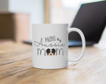 May include: White ceramic coffee mug with a black and brown mini Australian Shepherd dog illustration and the text "MINI Aussie MOM" in silver lettering.
