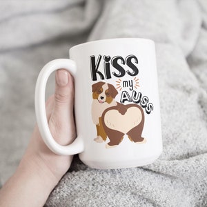 May include: White ceramic mug with a brown and white Australian Shepherd dog illustration. The text "Kiss my Aus" is printed on the mug.