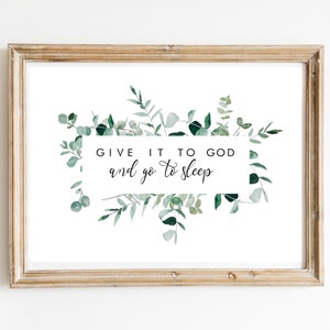 May include: A framed print with a white background and a green leafy border. The text in the centre reads "Give it to God and go to sleep."
