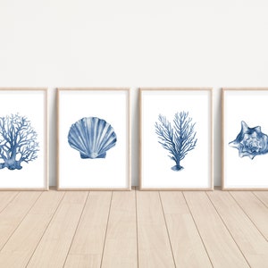 May include: Set of four blue watercolour prints featuring a seashell, two coral branches, and a conch shell. The prints are framed in natural wood frames and are perfect for a coastal-themed home decor.