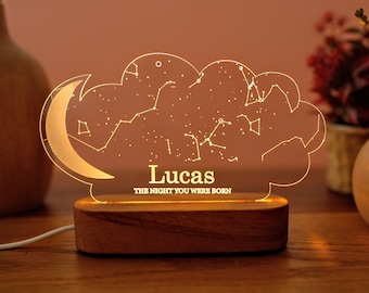 May include: A wooden night light with a clear acrylic insert shaped like a cloud with a crescent moon. The acrylic insert features a constellation design and the text "Lucas THE NIGHT YOU WERE BORN".