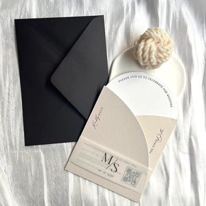 May include: A wedding invitation with a black envelope and a beige card with the text "Please join us to celebrate our wedding" and "The Pine Date" in a modern font. The card also includes a QR code and the date "09.11.2025".