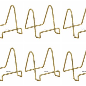 May include: Set of 8 gold metal display stands. Each stand is shaped like a triangle and has a twisted rope design.