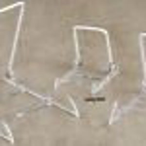 May include: Three clear acrylic display stands of different sizes. The stands are made of a sturdy, transparent plastic and have a simple, modern design.