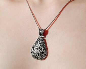 May include: A silver chain necklace with a silver pendant featuring an intricate black and silver filigree design.