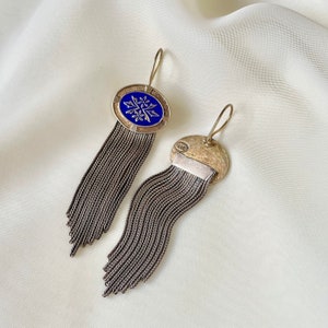K&ouml;nnte beinhalten: Silberne Ohrringe mit blauem Emaille-Ovaldesign und floralem Muster. Die Ohrringe haben lange, baumelnde Ketten. Der Hintergrund ist wei&szlig;.