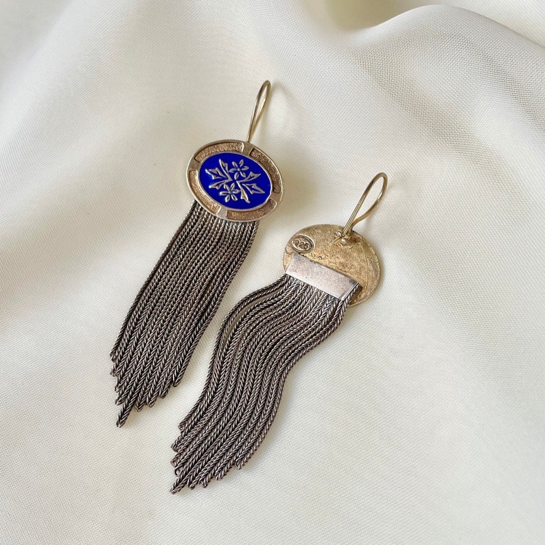 K&ouml;nnte beinhalten: Silberne Ohrringe mit blauem Emaille-Ovaldesign und floralem Muster. Die Ohrringe haben lange, baumelnde Ketten. Der Hintergrund ist wei&szlig;.