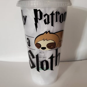 May include: Clear plastic tumbler with a green straw and lid. The tumbler has the text "Expecto Patronum" and "I'm a Sloth" in black, plus a cartoon sloth illustration. A fun, themed drinks container.
