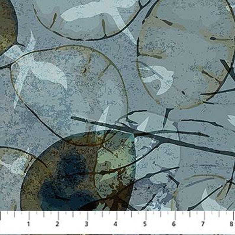 May include: Textile featuring a repeating pattern of large, overlapping, semi-transparent, circular shapes in shades of blue, green, and brown. White leaf-like shapes and dark brown branch-like lines are scattered across the surface. A ruler with inch measurements is at the bottom.