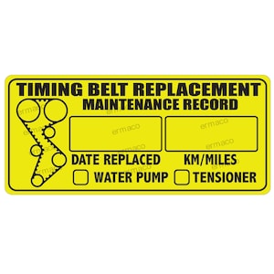 May include: Yellow sticker with black text that reads "Timing Belt Replacement Maintenance Record". The sticker has a diagram of a timing belt, two blank spaces for dates and mileage, and checkboxes for "Water Pump" and "Tensioner".