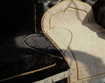 May include: Two prayer rugs with gold trim and fringe. One rug is black velvet and the other is beige.