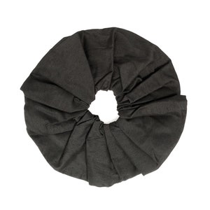 May include: A black fabric hair scrunchie, folded into a circle shape.