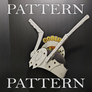 May include: A white headpiece featuring two tall, angled, blade-like projections extending upwards from a central band. The structure is secured with metallic gold rivets and displays faint line drawings. The word PATTERN appears twice.