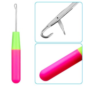 Puede incluir: Una aguja de lana rosa y verde con un gancho de metal. La aguja tiene una punta puntiaguda y un bucle en el extremo del gancho.