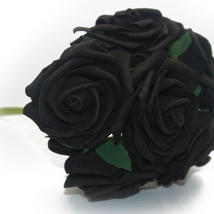 May include: A bouquet of five black artificial roses with green stems and leaves.