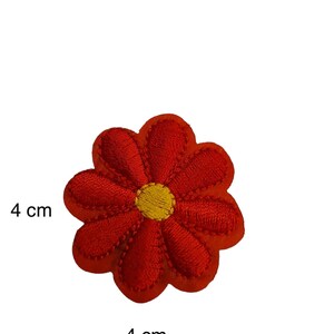 May include: Red embroidered flower patch with a yellow centre, measuring 4 cm in diameter.