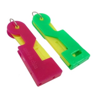 May include: Two plastic needle threaders, one green and one pink, with yellow accents. Both threaders have a small metal loop at the top and the text "Made in China" is printed on the pink threader.