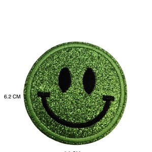 May include: Green glitter smiley face iron-on patch, 6.2 inches in diameter.