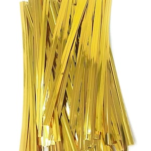 May include: A large pile of gold twist ties. The ties are made of thin, shiny metal and are ideal for tying up gifts or crafts.