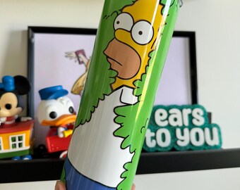 Op de afbeelding: Een geel cartoonfiguur met een blauwe spijkerbroek en een groene achtergrond. Het figuur kijkt uit achter een struik. De tekst "ears to you" is zichtbaar op de achtergrond.