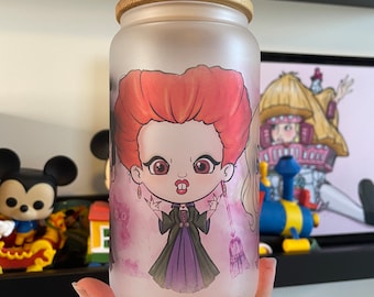May include: A frosted glass jar with a bamboo lid featuring a cartoon illustration of three witches. The witches are wearing colorful dresses and have large eyes. The jar is decorated with a pink and purple background.