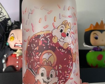 Op de afbeelding: Een matglazen pot met een houten deksel met een cartoon afbeelding van twee eekhoorns met een donut en sprinkels.