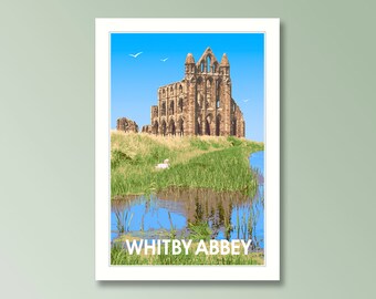 May include: A rectangular art print featuring the stone ruins of Whitby Abbey under a bright blue sky. The scene includes green grassy fields, a small body of water reflecting the sky, and the white text WHITBY ABBEY at the bottom.