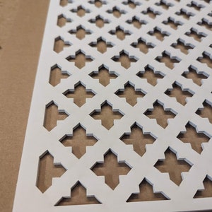 May include: White decorative metal sheet with a repeating geometric pattern of diamond shapes. The sheet has a grid-like design with cut-out shapes.