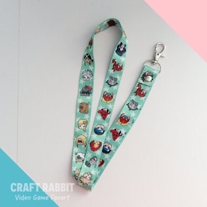 May include: A light green lanyard with a repeating pattern of cartoon character faces and white stars. The lanyard has a silver-colored clasp and a snap closure. The text "CRAFT RABBIT Video Game Fanart" is printed at the bottom left.