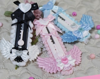 Puede incluir: Tres cúteres decorativos en negro, rosa y azul, adornados con lazos de cinta, encaje y adornos en forma de corazón. Los cúteres tienen pequeñas alas y el texto "CRAFT RABBIT KAWAII" es visible.