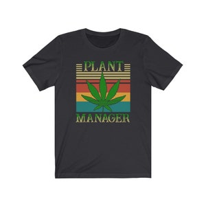 May include: Black t-shirt with a retro-style graphic of a marijuana leaf and the text "PLANT MANAGER".